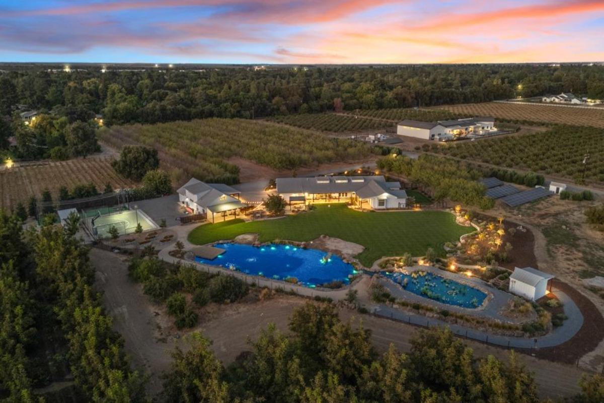 Aerial view of a large property with a house, pool, and orchard.