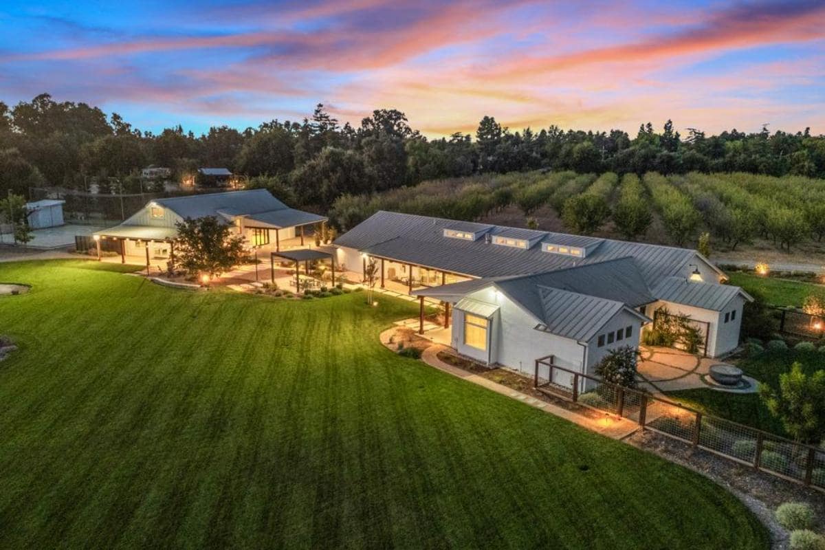 Aerial view of a large property with a house, pool, and orchard.