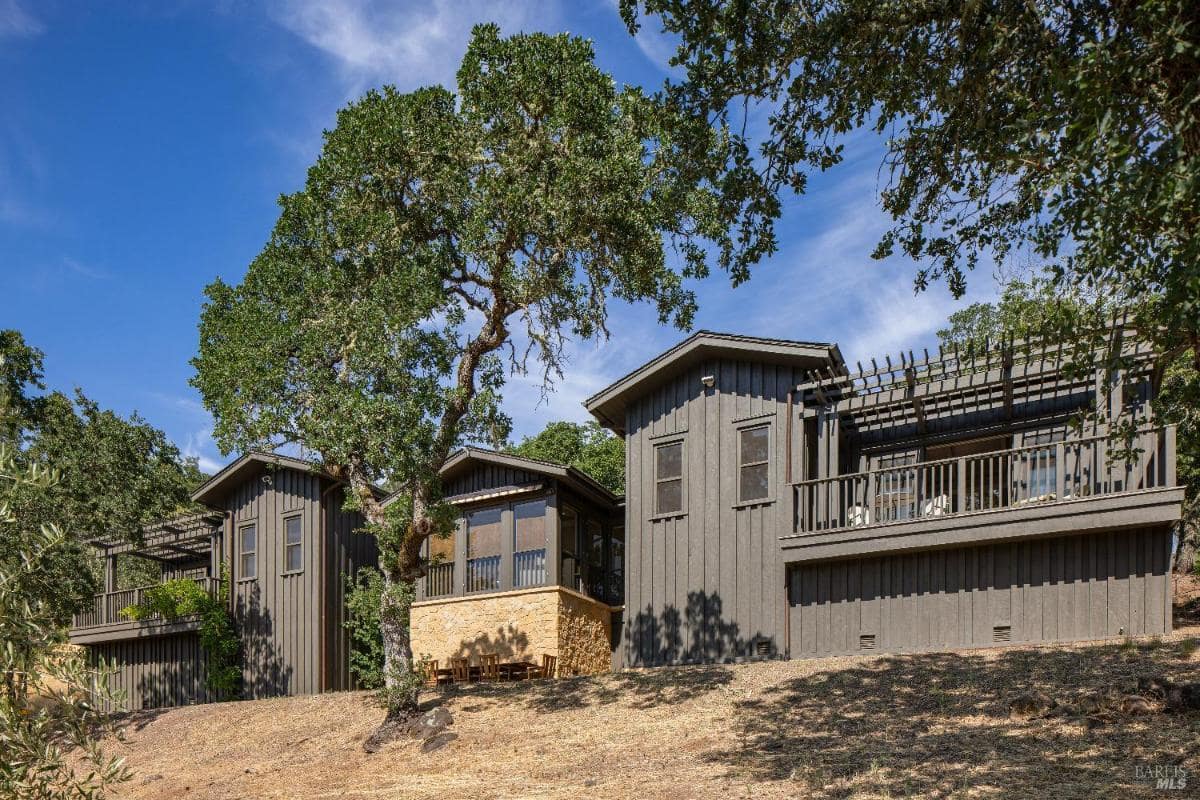 Dark-painted hillside house with multiple levels and balconies.