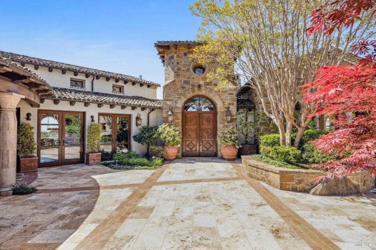 An entrance to a home featuring a large wooden door framed by stone walls.