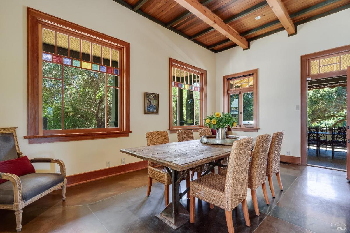 Dining room with a wooden table, wicker chairs, and stained glass windows.