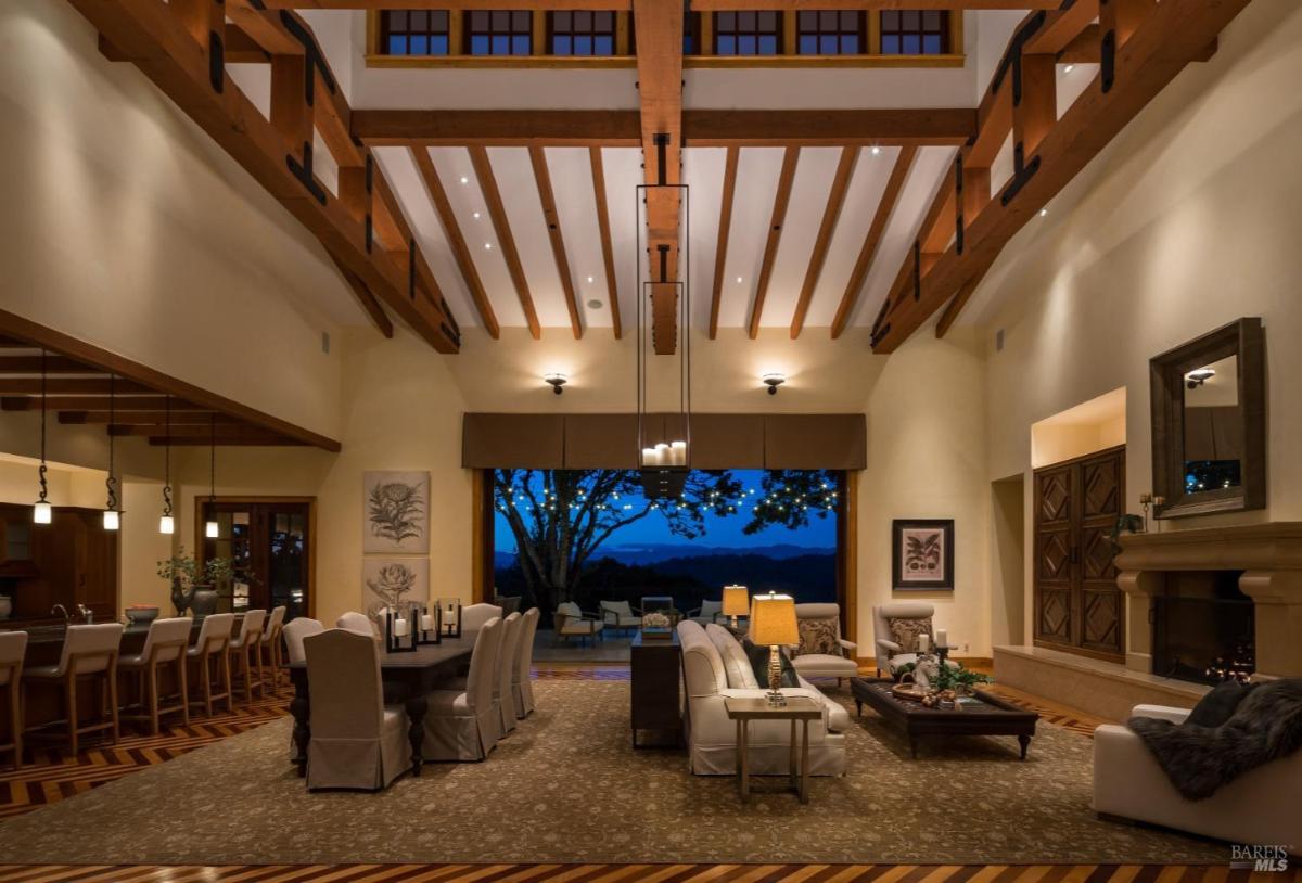 Evening interior of a living room with visible outdoor seating through open doors.