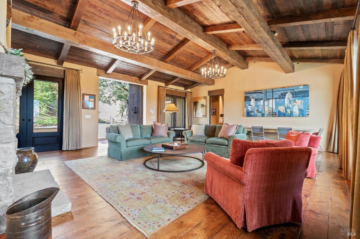 Living room with sofas, a fireplace, and large wooden beams on the ceiling.