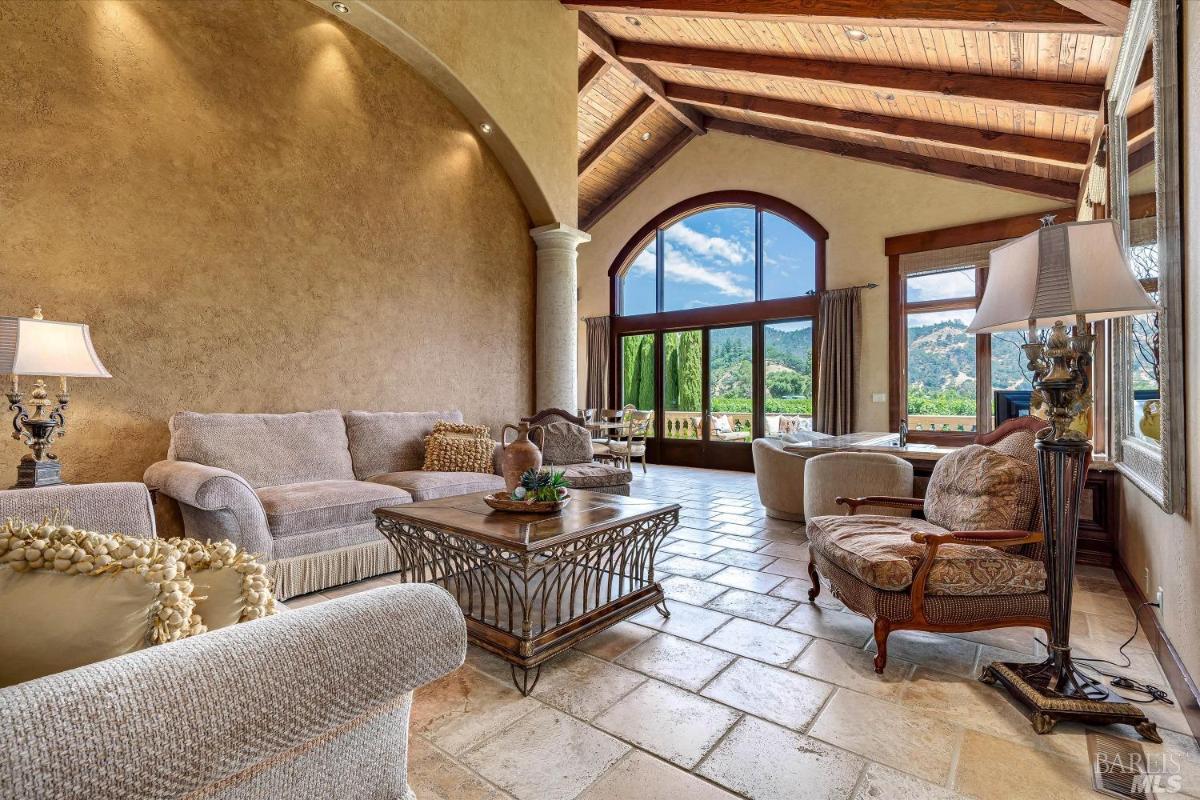 Living room with large windows, seating arrangements, and a high vaulted ceiling.