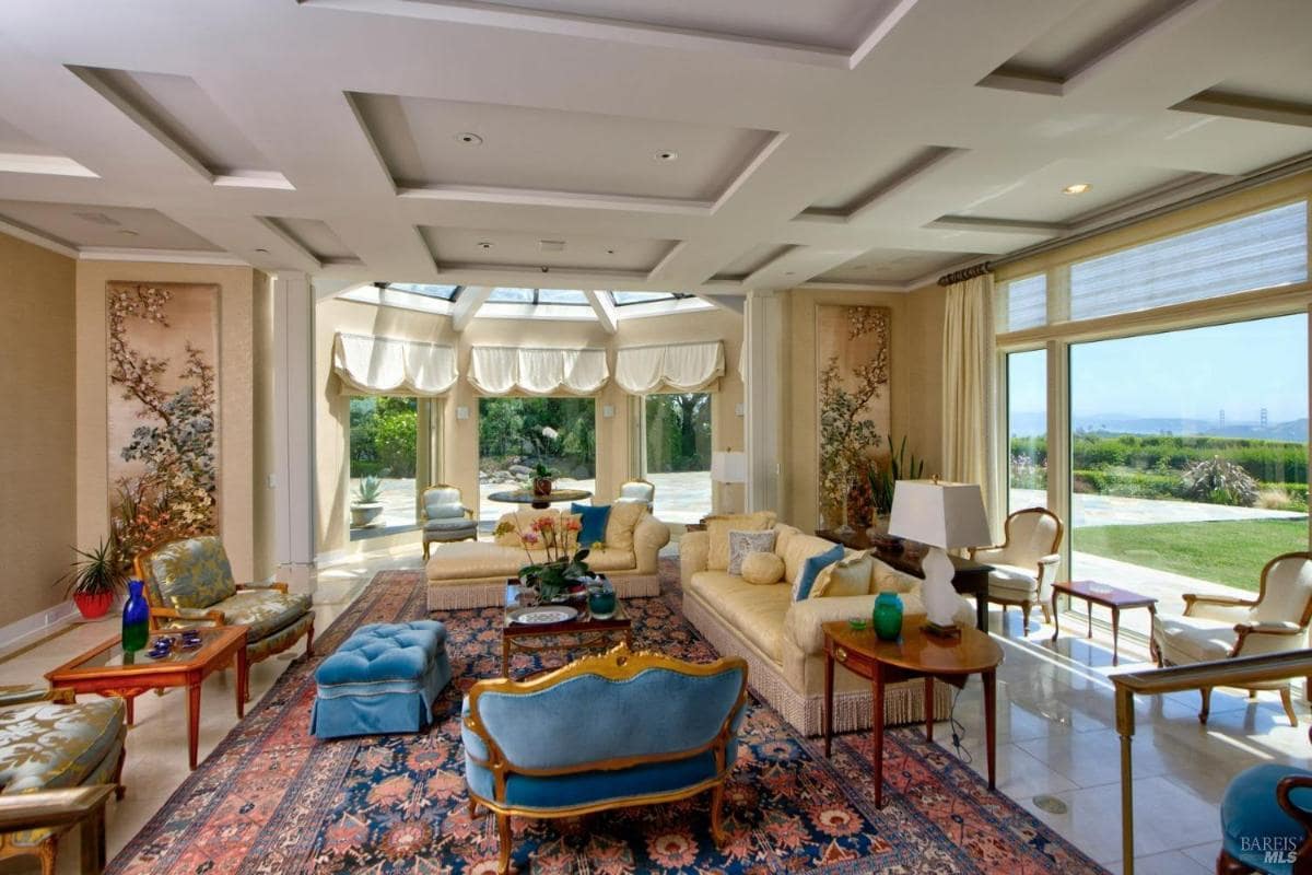 Living room with coffered ceilings, a glass dome skylight, and large windows offering views of the garden. 