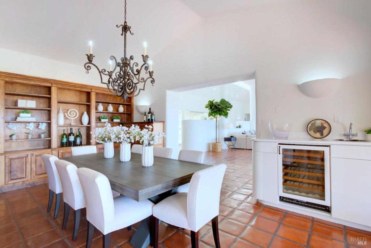  A dining area with a wooden table, chairs, and a hanging chandelier.