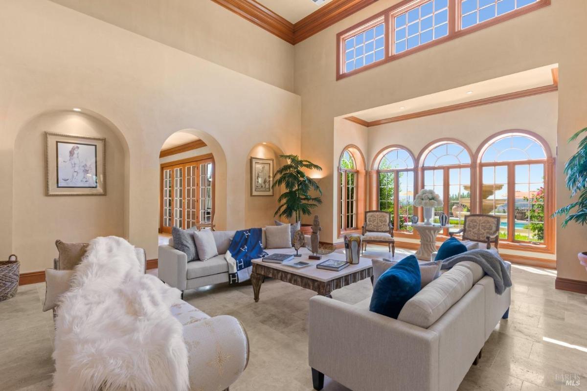 Living room with arched windows, seating arrangements, and natural light complementing the serene garden view.