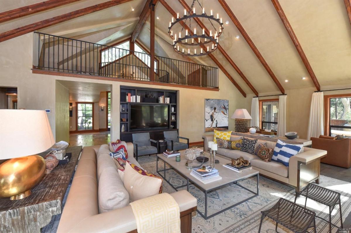 A living room with vaulted ceilings, a chandelier, and a mezzanine above.