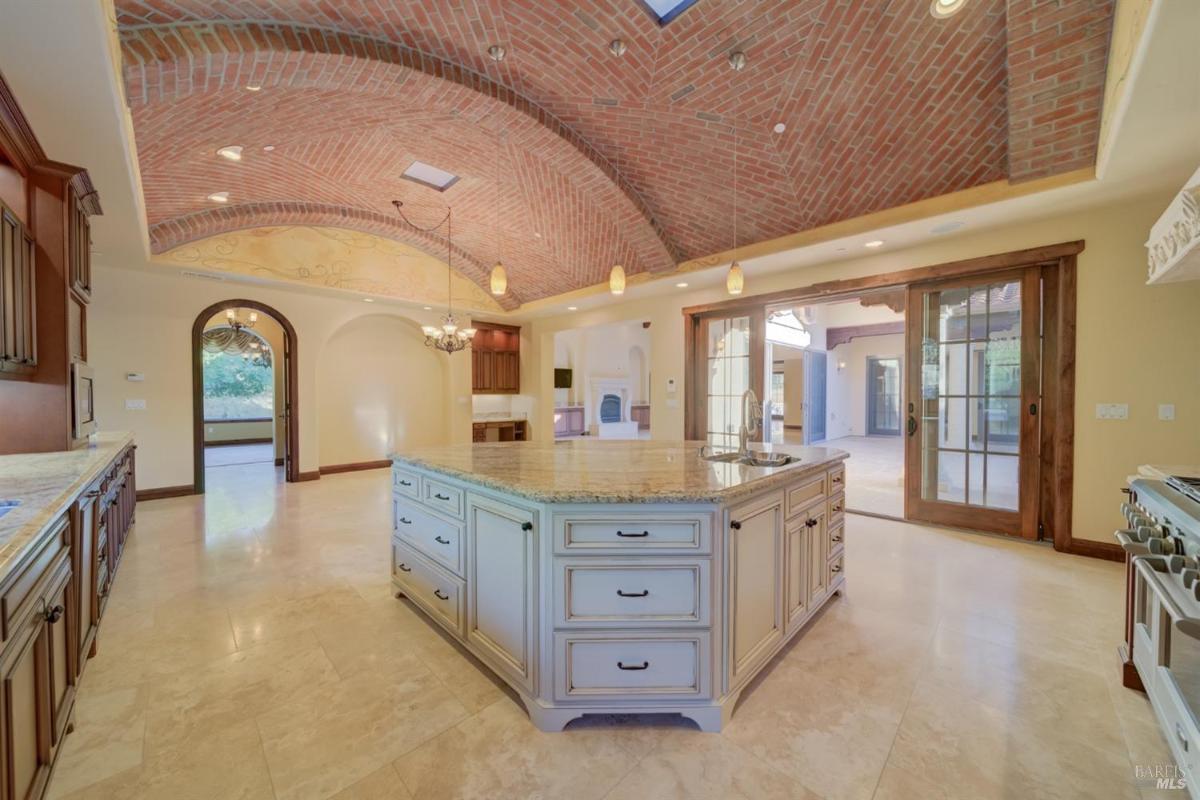 A kitchen featuring a large island, brick arches, and wooden cabinetry.