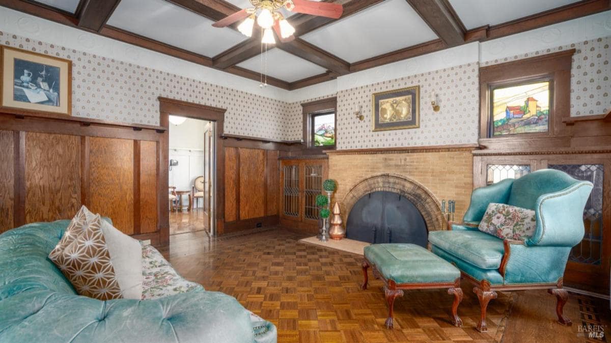 Sitting room with wood paneling and a large fireplace.