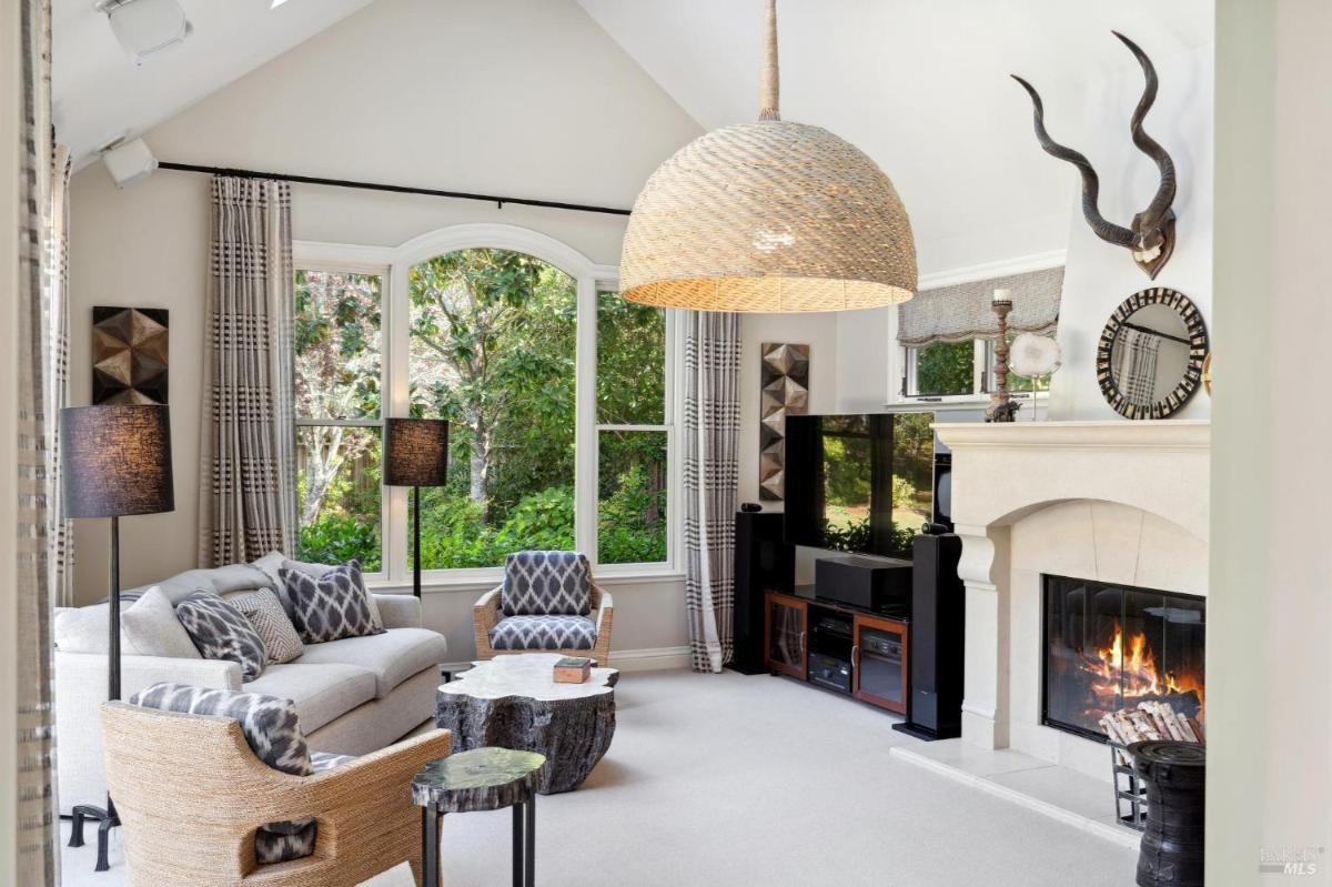 Family room with a fireplace, large windows, and a television.