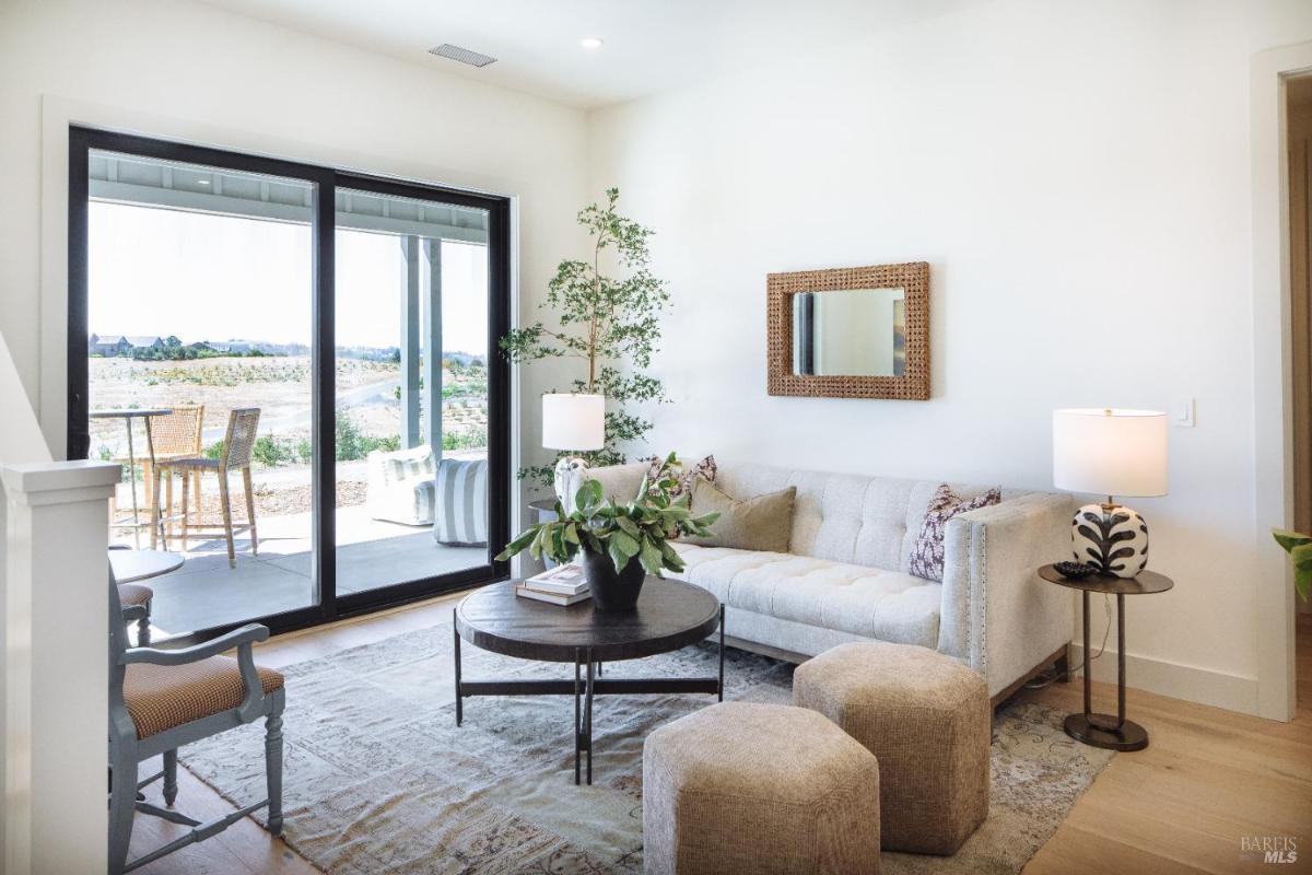 A living room with a sofa, table, and a view of the outside landscape.