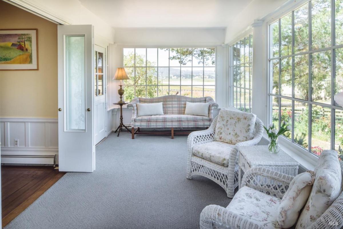 A sunroom with wicker furniture and large windows.