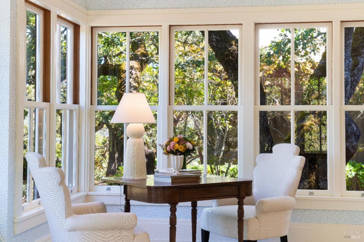 Small seating area with two chairs and a table, surrounded by large windows.