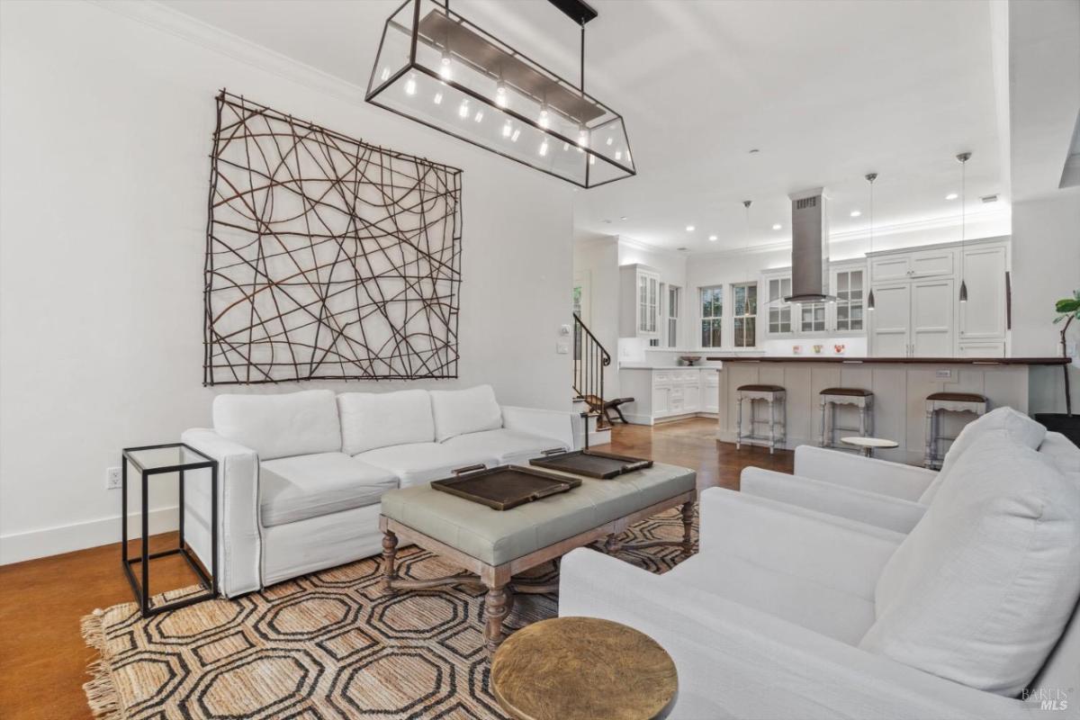 Living room with white furniture, a TV, and a geometric-patterned rug.