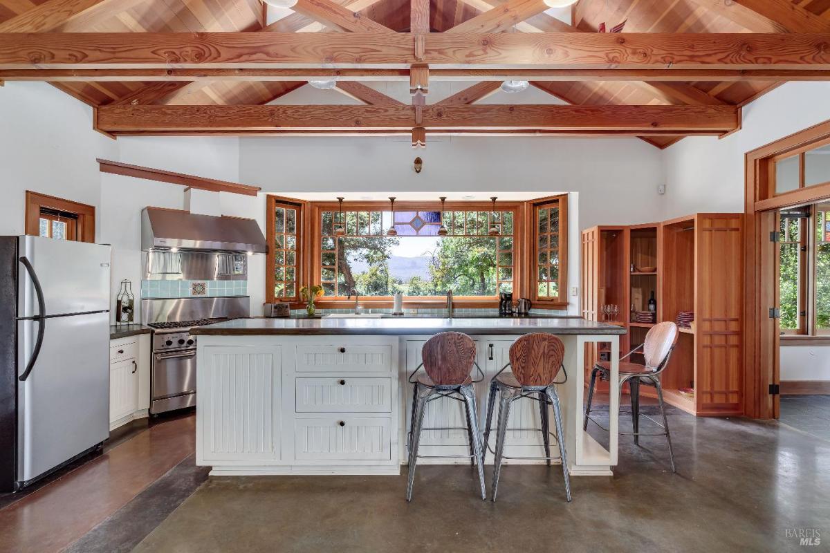 Kitchen with stainless steel appliances, central island, and open windows with views.