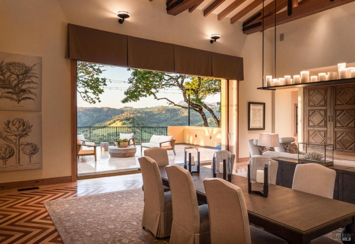 Dining area overlooking an outdoor terrace and hilly landscape.