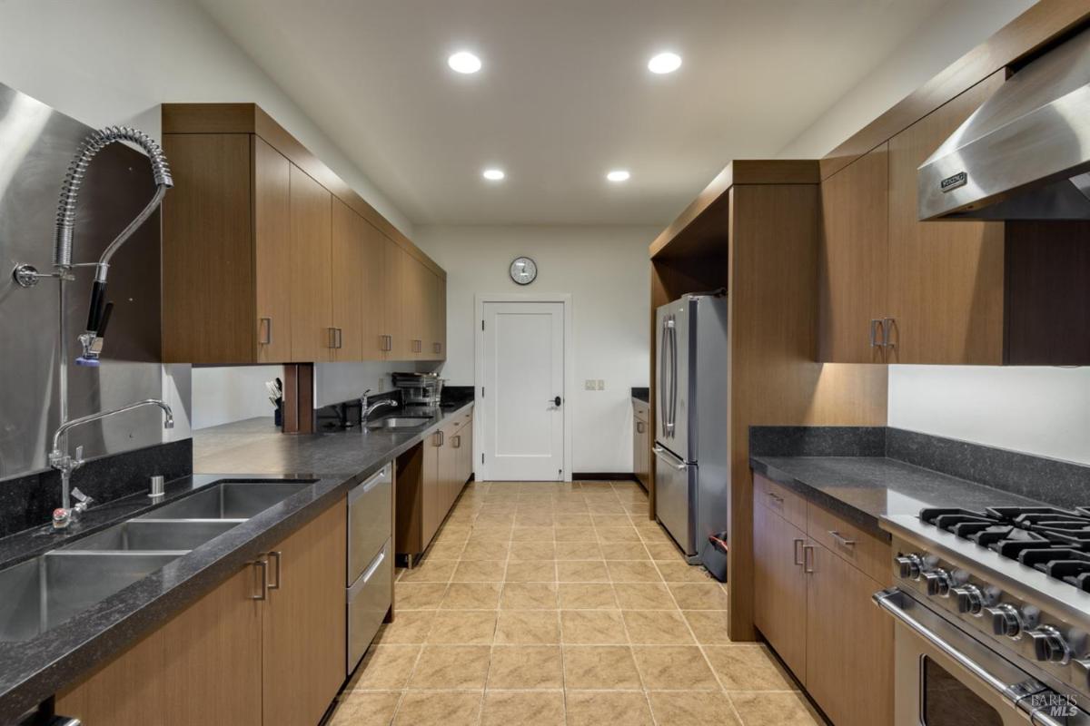 Narrow kitchen with stainless steel appliances and wood cabinets.