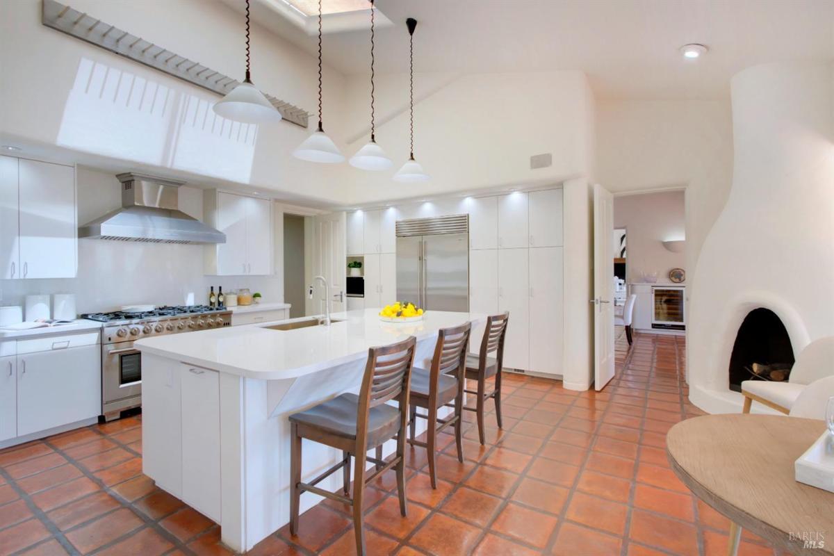 A bright kitchen featuring a central island, barstools, and built-in appliances.