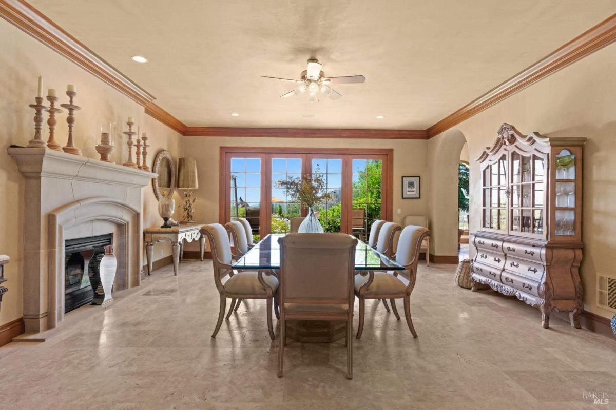 Dining area includes a stone fireplace, glass doors, and a large table surrounded by upholstered chairs.