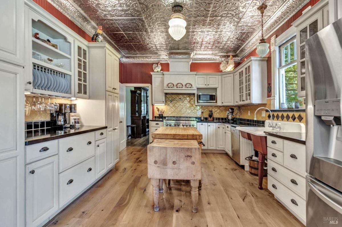 A kitchen with white cabinetry, a center island, and decorative ceiling tiles.