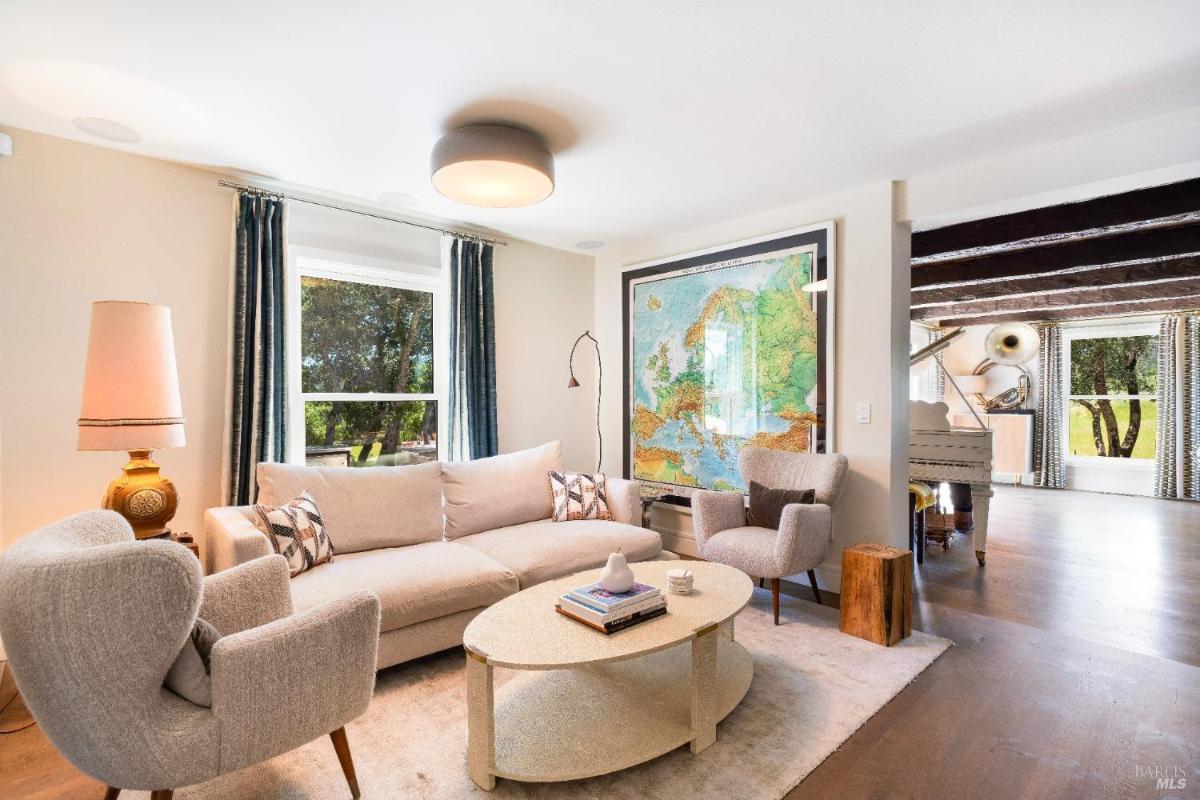 Lounge area with sofa, chairs, and large wall map beside a piano room.