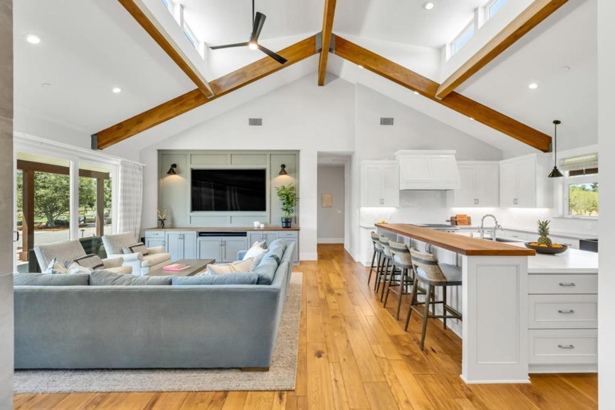 A living and kitchen space with vaulted ceilings and a large island with barstools.