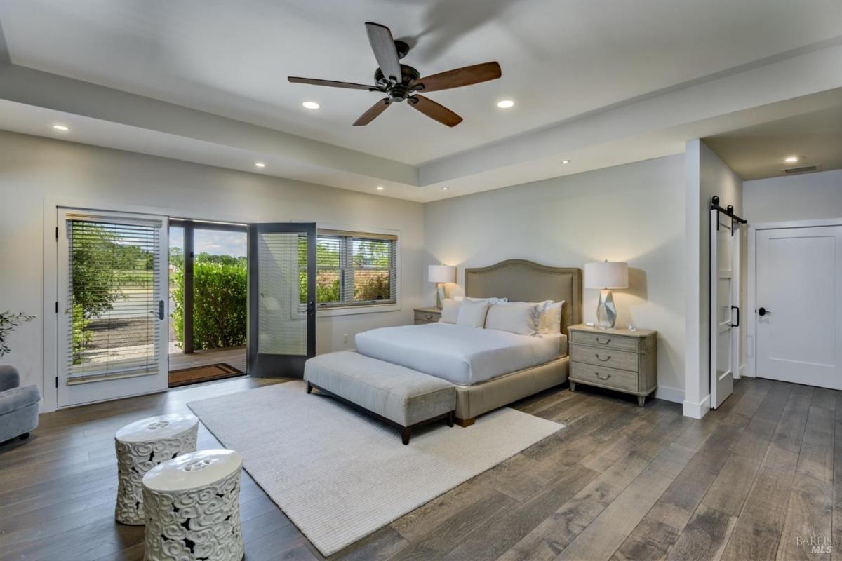 Bedroom with a king-sized bed, ceiling fan, and doors leading to an outdoor patio.