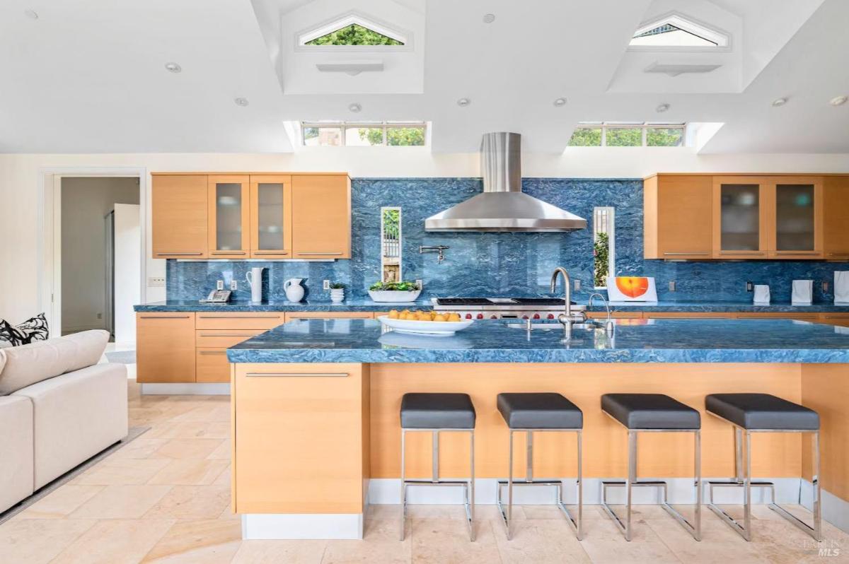 Kitchen with blue countertops, wood cabinets, and a large island with stools.