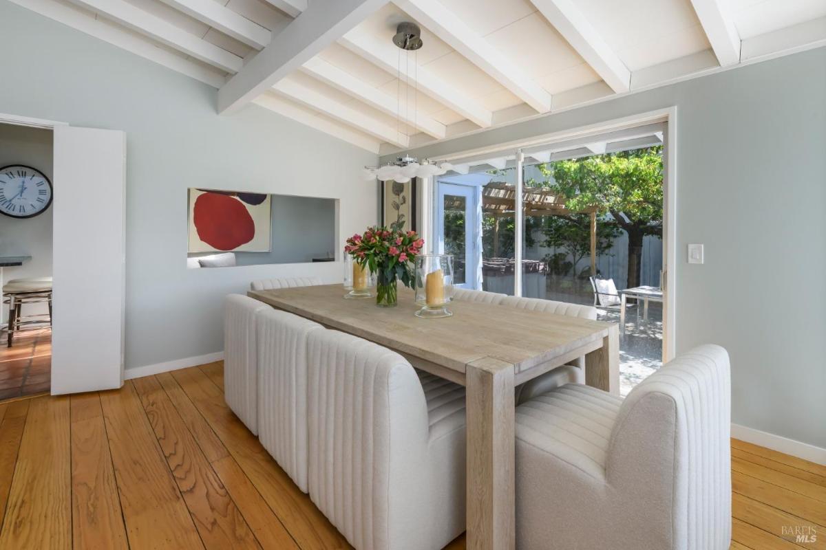 A dining room with a wooden table, upholstered chairs, and sliding glass doors leading to a patio.