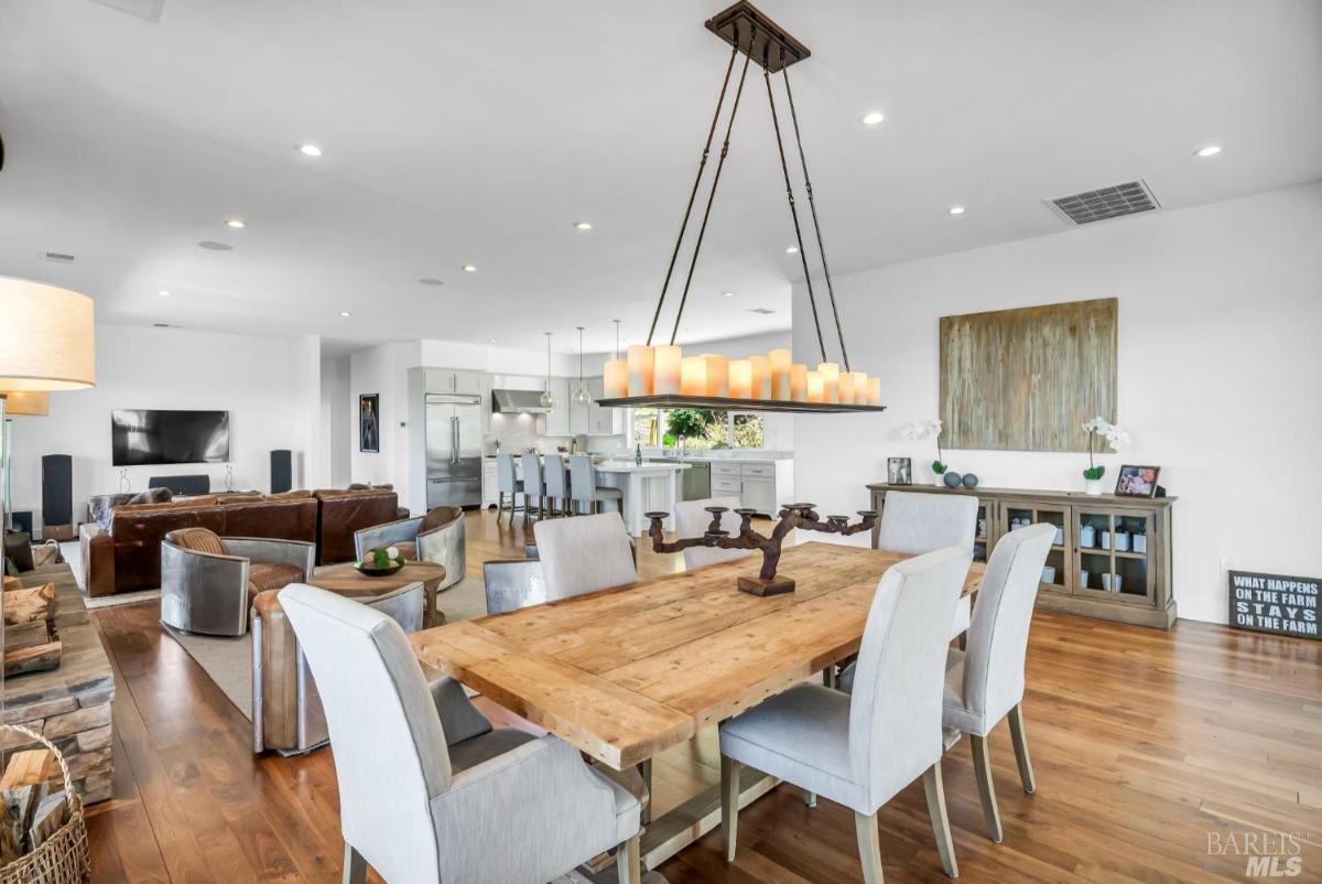 A dining area with a wooden table, upholstered chairs, and a large light fixture. 