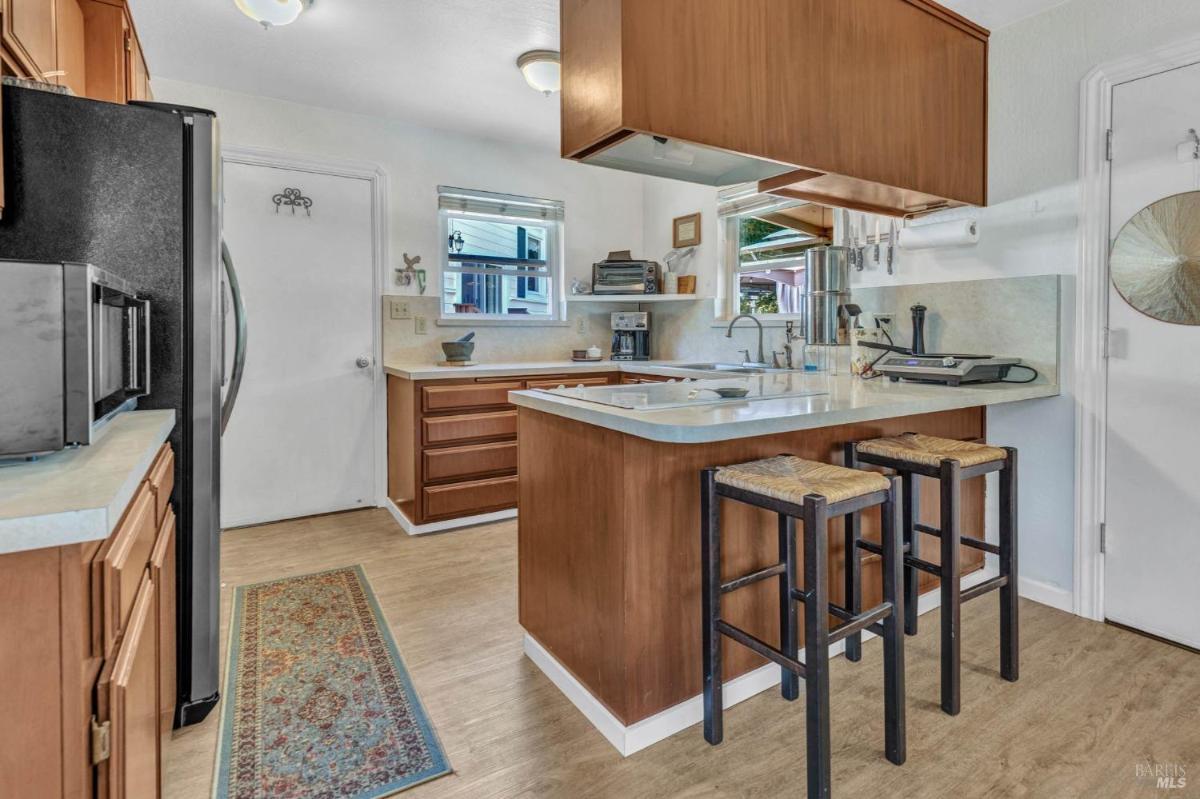 A compact kitchen with wooden cabinets, a breakfast bar, and barstools.