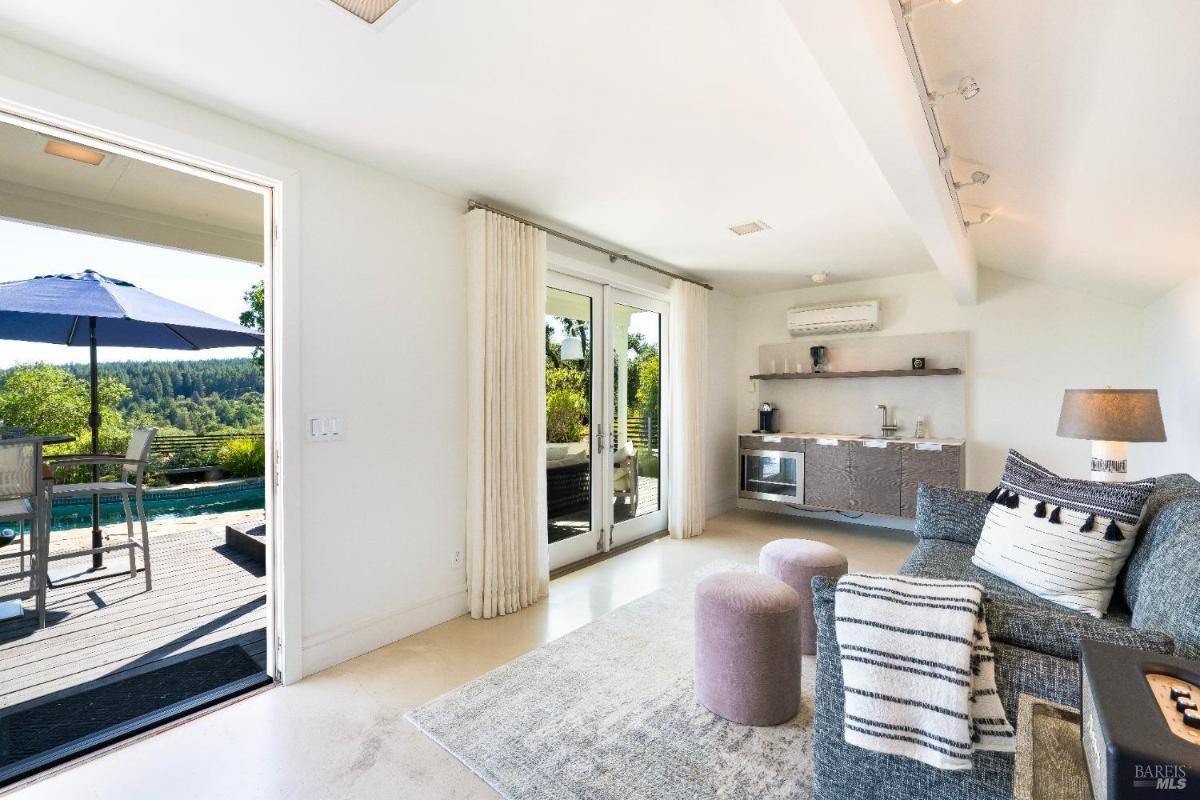 Room with seating, small kitchenette, and doors leading to a pool deck.