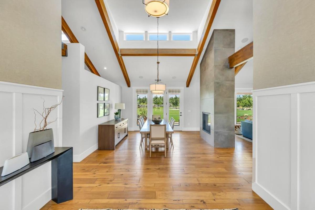 A dining area with a fireplace, high ceilings, and a view of the backyard.