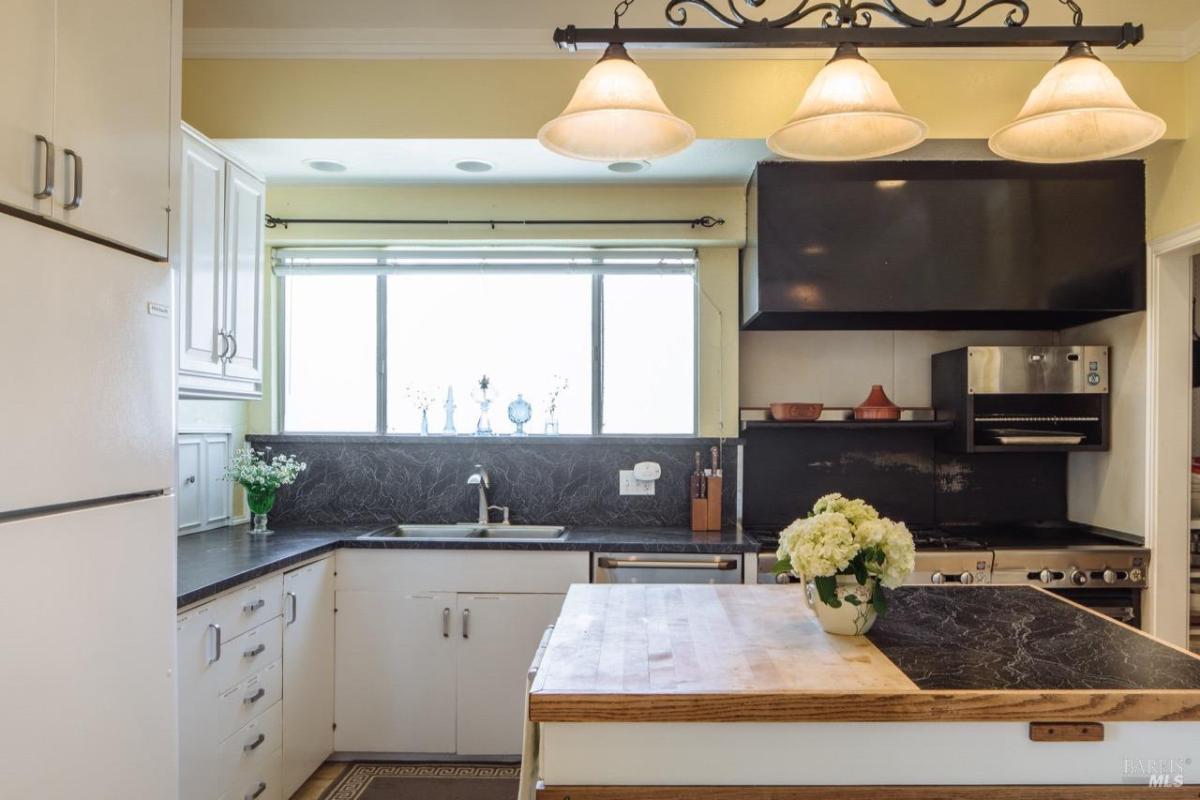 Kitchen with white cabinets, black countertops, and a large center island.