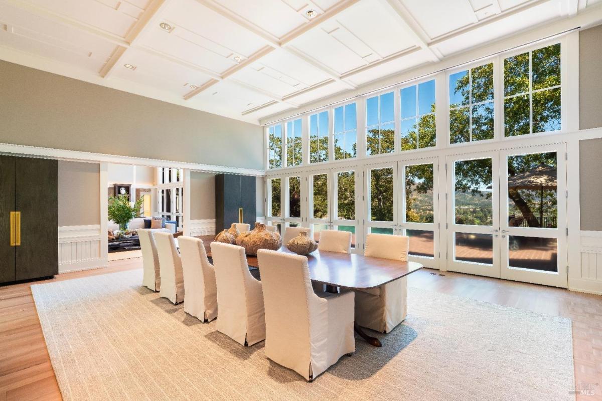 Dining room with a long table, upholstered chairs, and glass doors leading to a ter