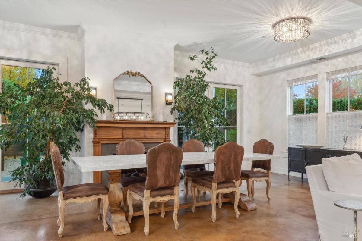 Dining area with a long table, brown chairs, and a fireplace.