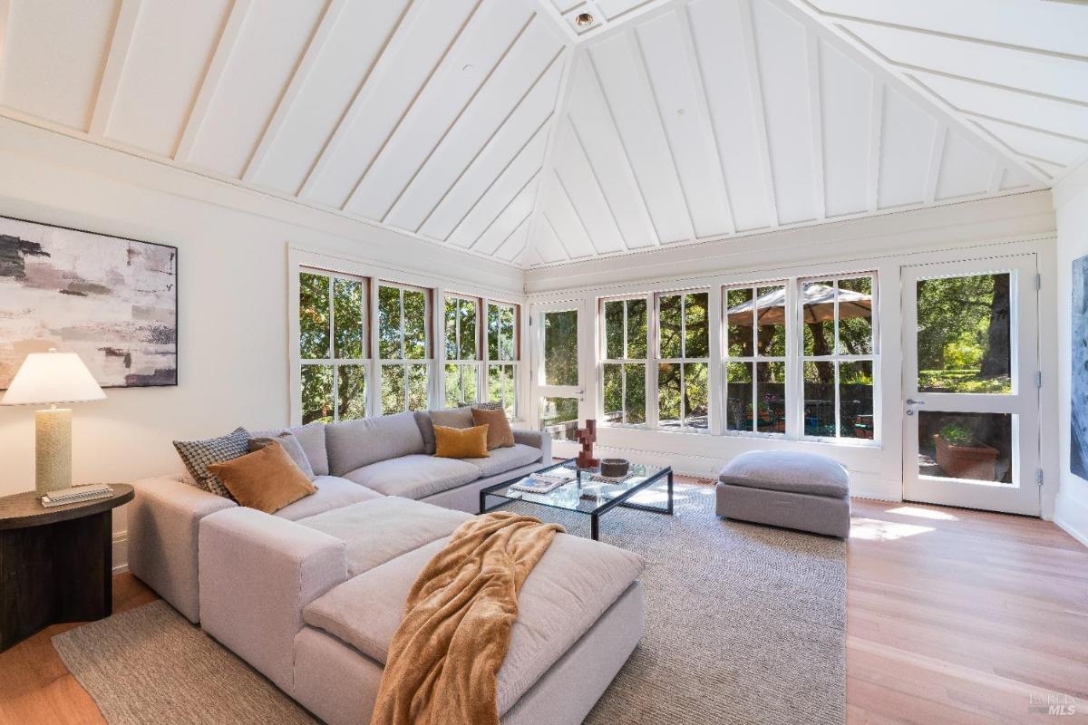 Family room with a sectional sofa, a glass table, and windows looking out to a patio.