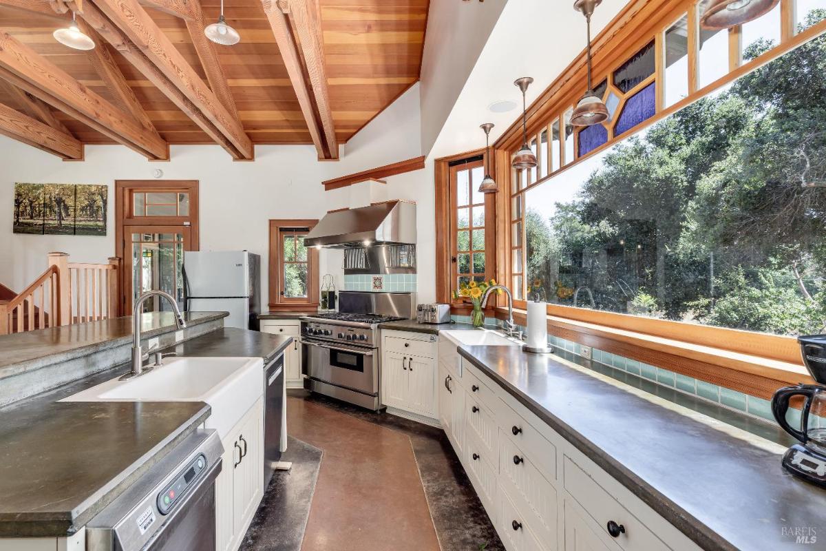 Kitchen with wood beam ceiling, large window, and stainless steel appliances.