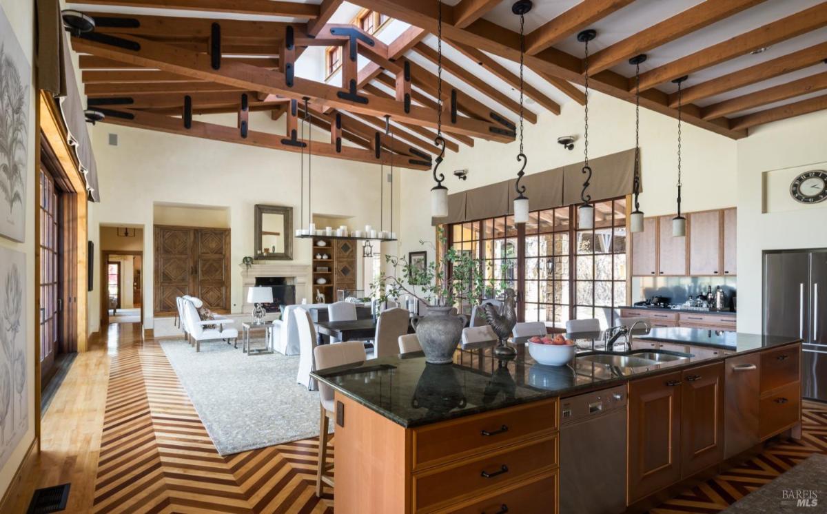 Combined kitchen, dining, and living area with wood ceilings and natural light.