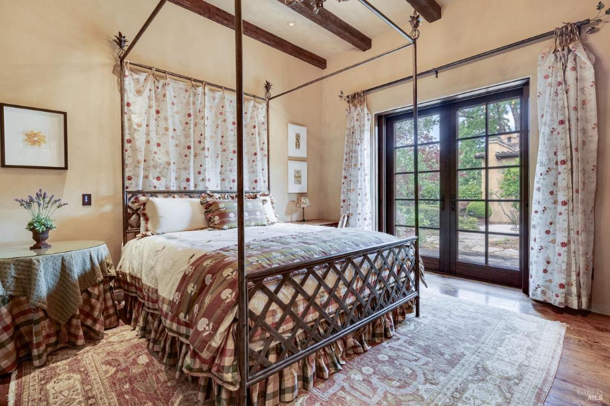 Bedroom with a four-poster bed, curtains, and French doors.