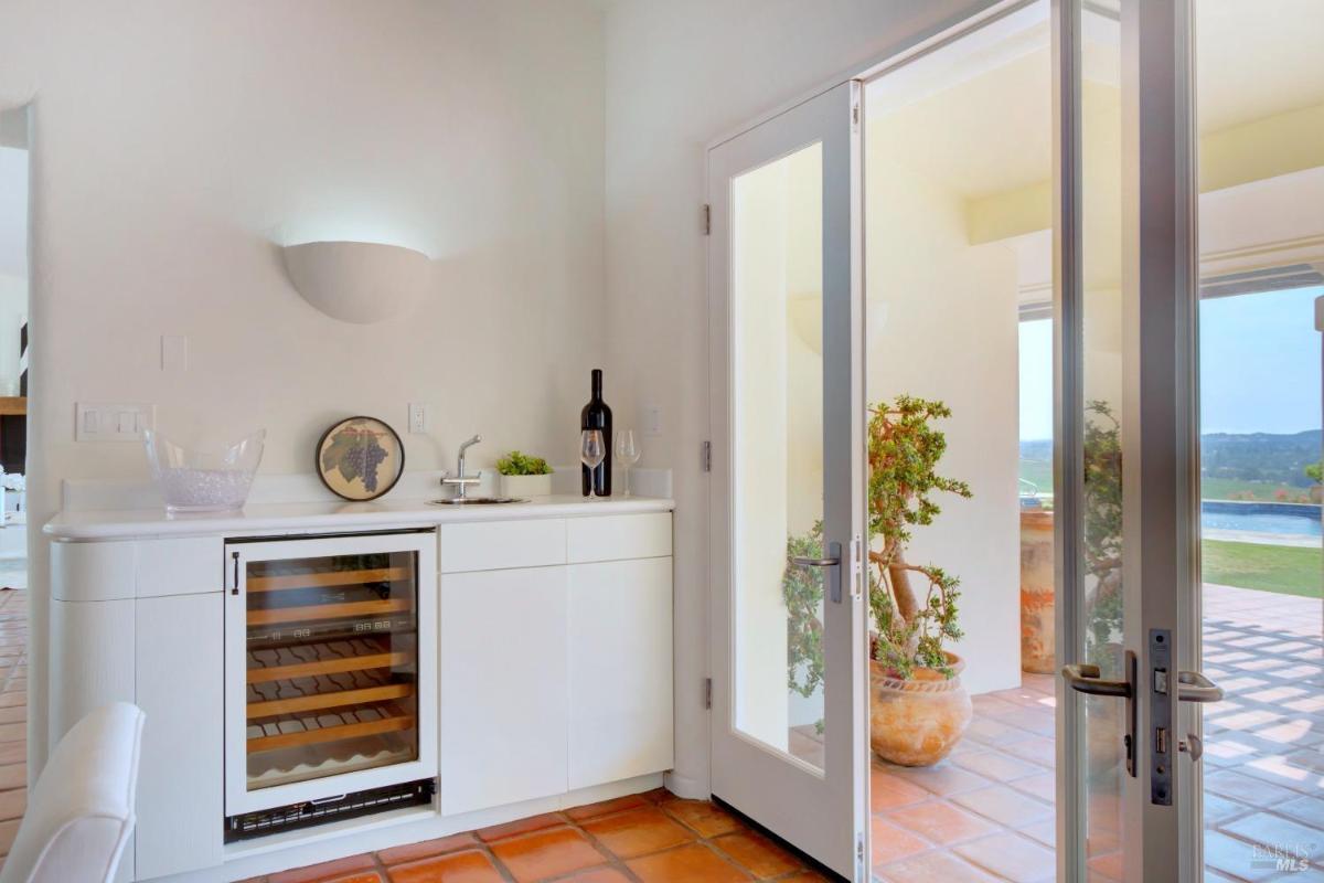 A small bar area with a wine cooler and countertop.