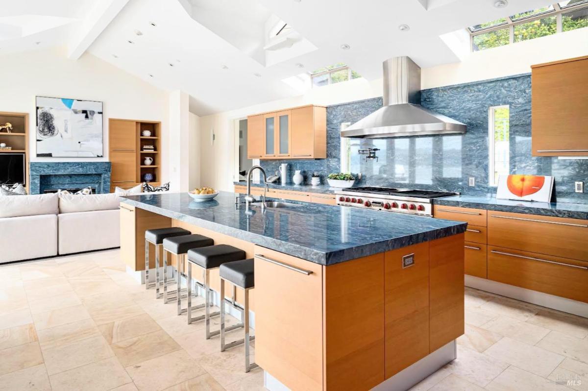 Kitchen view with blue stone counters, island seating, and an adjacent living space.