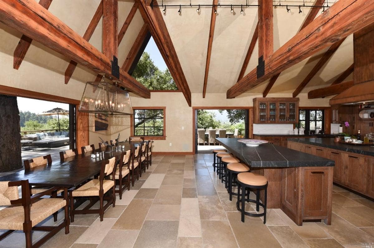 A kitchen and dining area with a large island, high ceilings, and outdoor access.