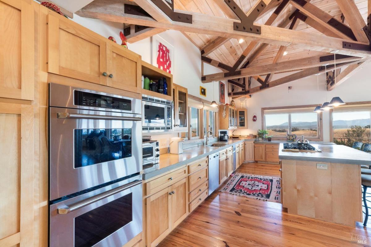 Kitchen with a central island, bar seating, and wooden cabinetry under vaulted ceilings.