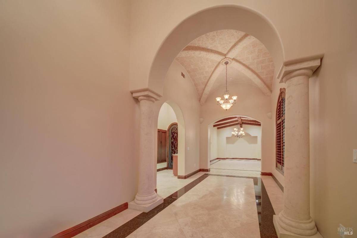 A spacious hallway with chandeliers and arched doorways. 