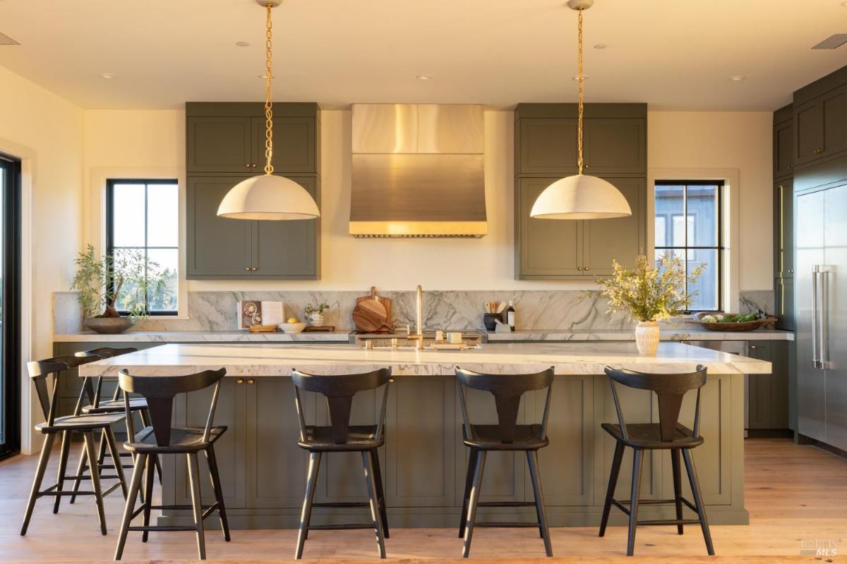 A modern kitchen featuring a large island with bar seating, pendant lighting, and stylish cabinetry. 