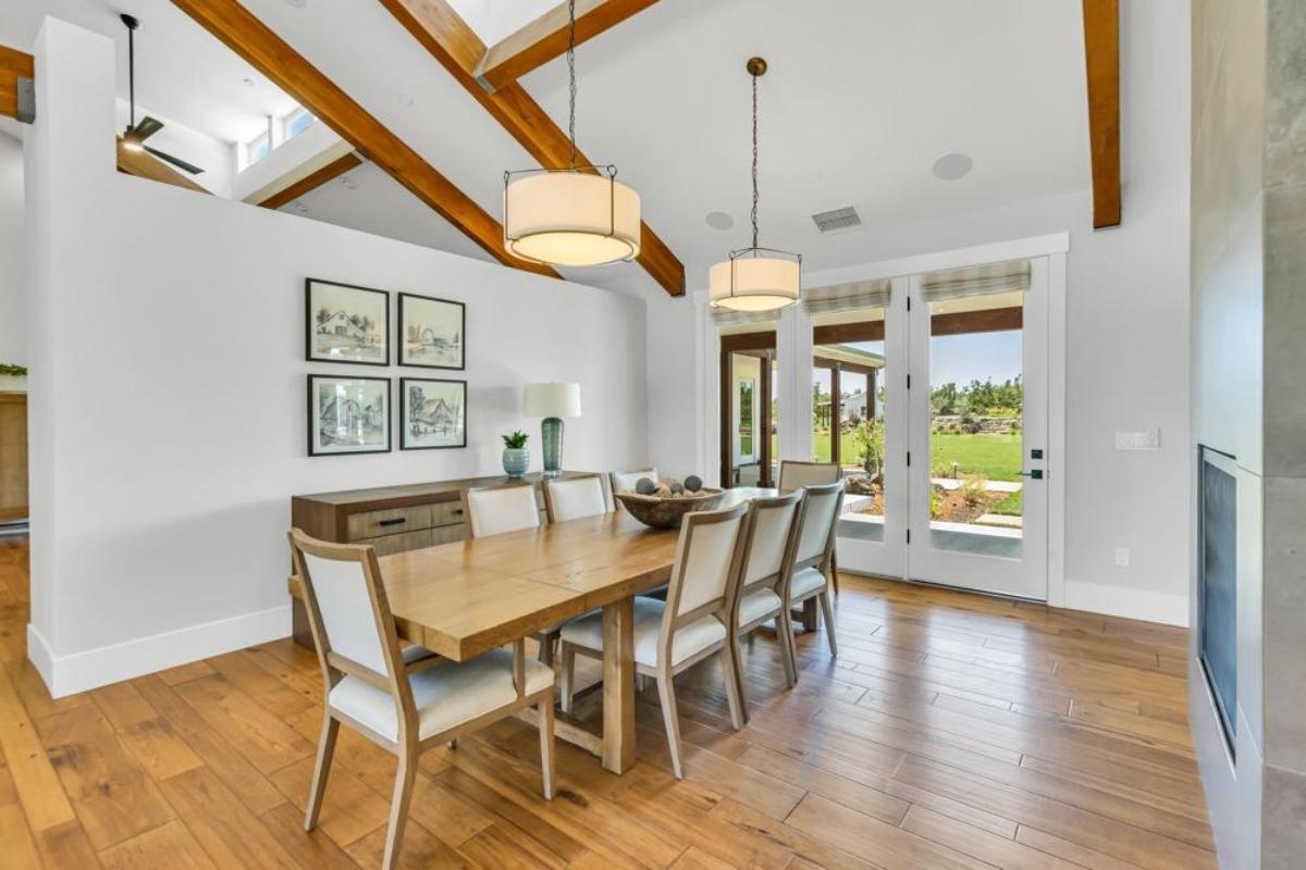 A dining room with a table, chairs, and large windows opening to an outdoor view.