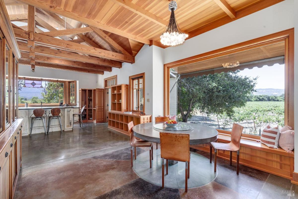 Breakfast area with a round table, large windows, and wood beam ceiling.