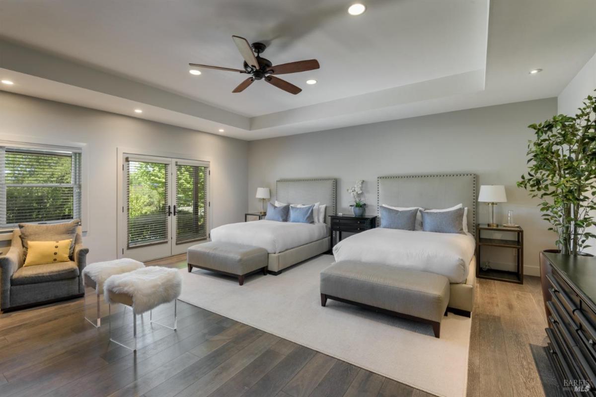 Bedroom with two beds, a ceiling fan, and a seating area.